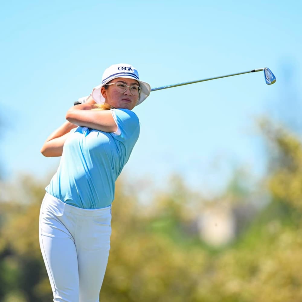 Golfer in blue attire performing a swing on the course