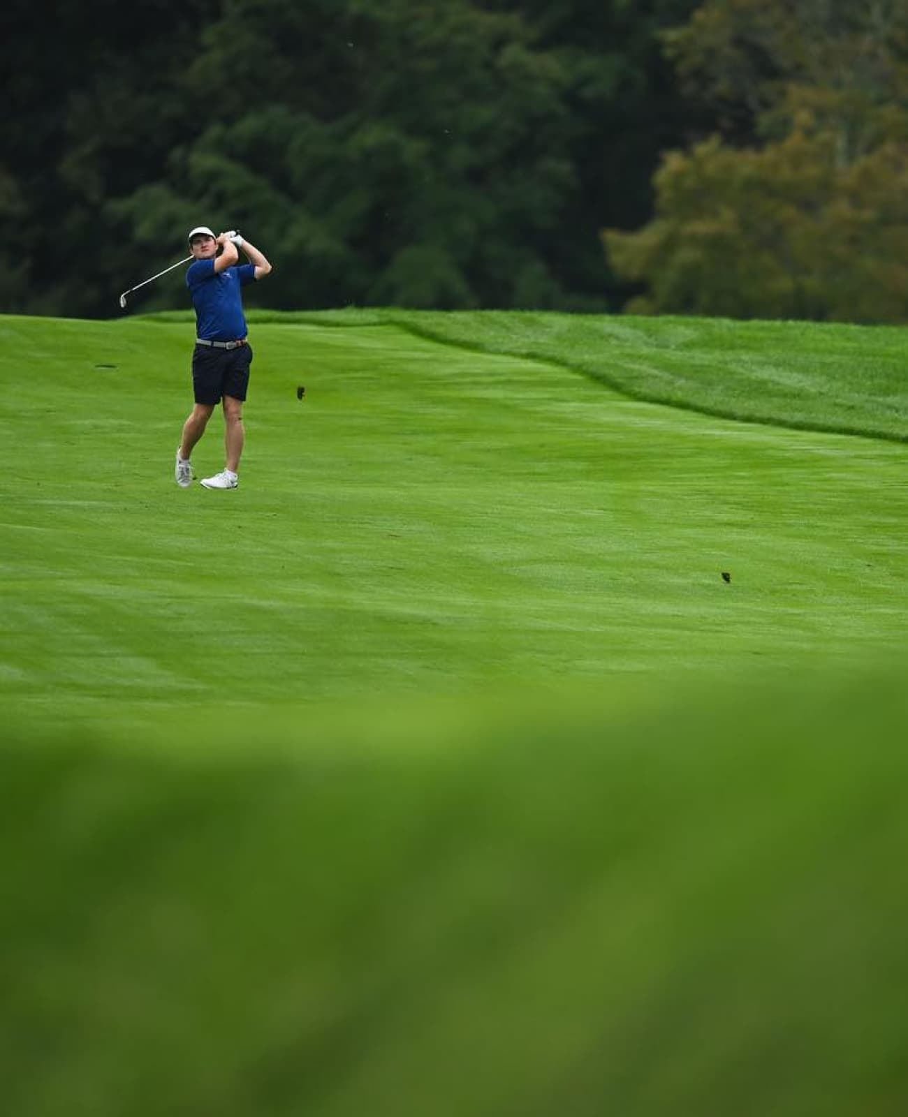 Close up on the green with a golfer in the background.