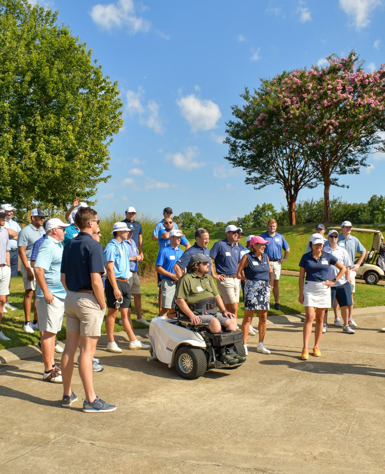 A large group gathered around a golfer in an accesibile golf cart.