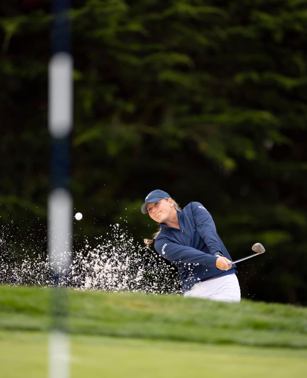 Female golfer chipping toward the putting green in foreground
