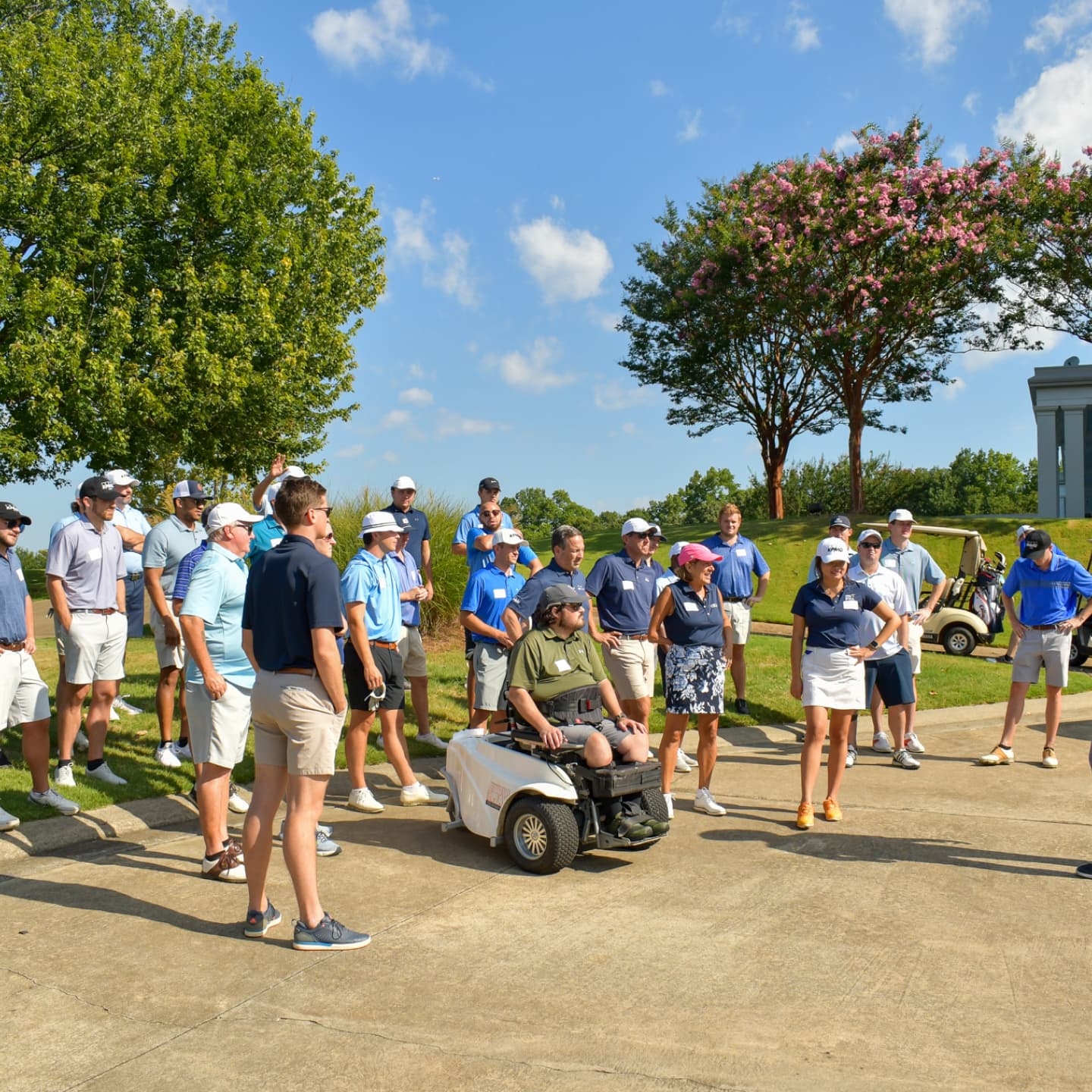 A large group gathered around a golfer in an accessibile golf cart.