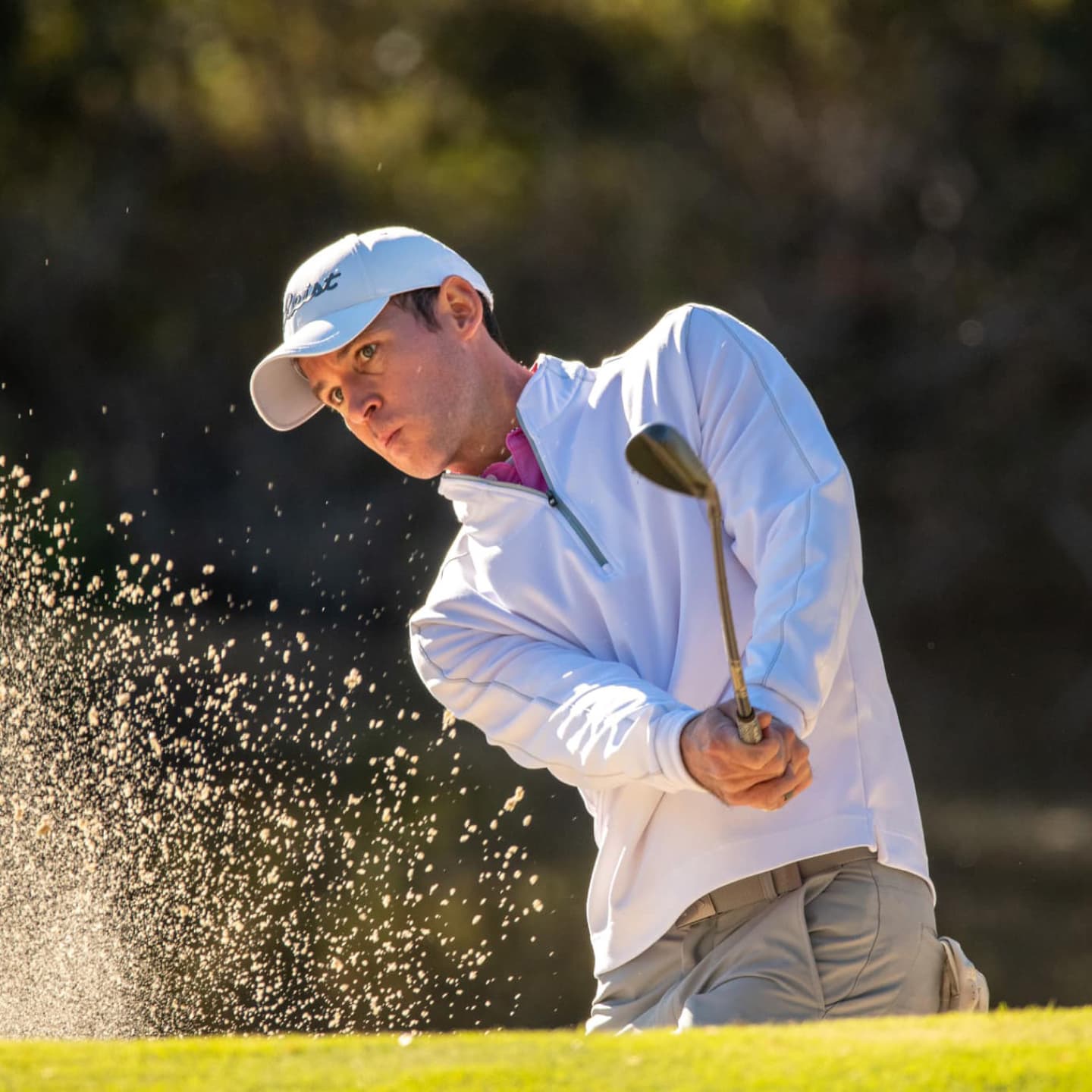 Golfer hitting out of a sand trap.